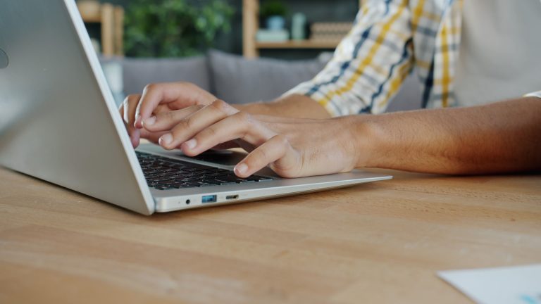 Close-up of hands typing on a laptop indoors, ideal for business and tech themes