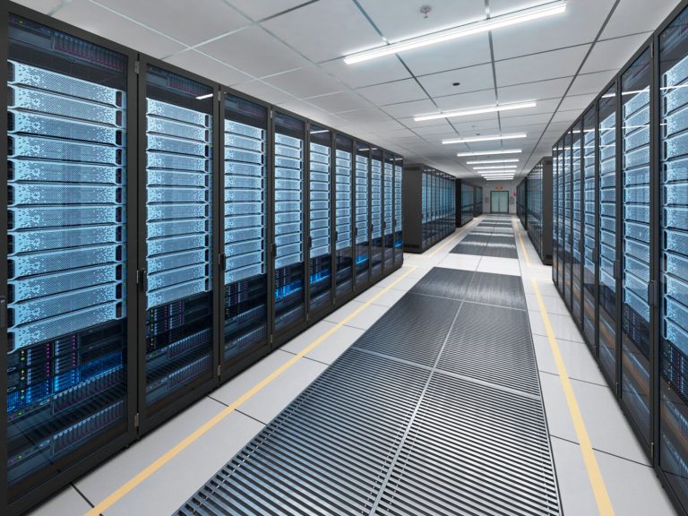 A bright data center hall with long rows of server racks and floor vents