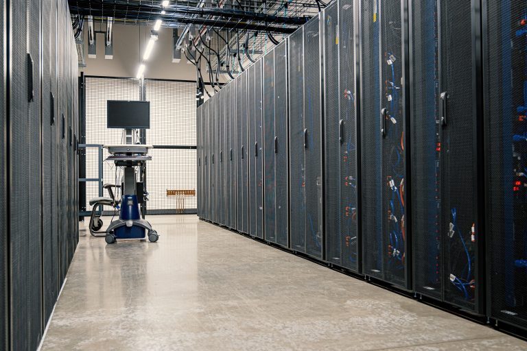 Rows of server racks with cables beside a workstation in a data center